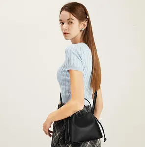 Side view of black lychee grain leather bucket bag with drawstring and adjustable strap