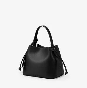 Detail of black litchi grain texture on minimalist bucket bag with drawstring accents