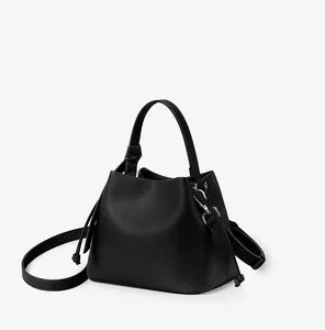 Detail of black pebbled leather bucket bag with top handle and metal hardware hooks