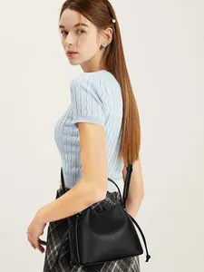 Close-up of a black lychee texture leather bucket bag worn as a crossbody by a model
