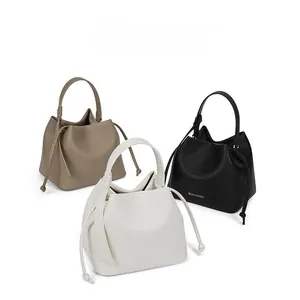 Three leather drawstring bucket bags in khaki, beige, and black with pebbled texture