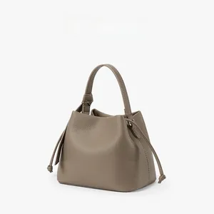 Detail of taupe pebbled leather bucket bag featuring decorative side drawstrings