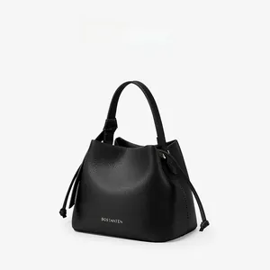Detail of black pebbled leather bucket bag with top handle and brand lettering