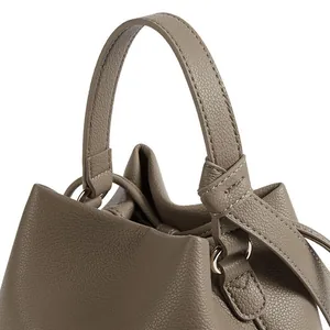 Close-up of taupe bucket bag showing premium lychee grain leather and drawstring detail