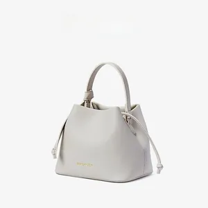 Close-up of off-white lychee textured leather bucket bag with knotted side drawstring detail