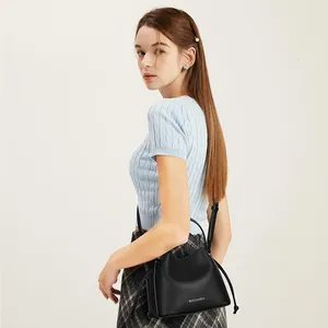 Detail showing the textured lychee grain leather and logo of this black shoulder bag