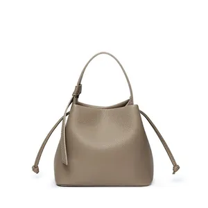 Minimalist khaki bucket handbag in pebble leather with top handle and drawstring details