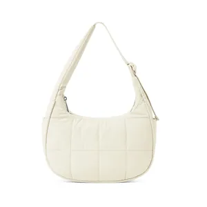 Detail of cream-colored quilted nylon crescent bag with adjustable shoulder strap