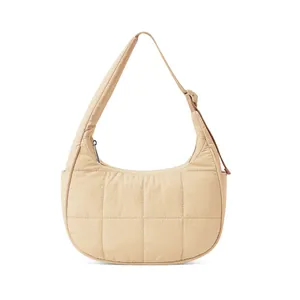 Detail of beige quilted nylon crescent bag featuring adjustable strap and puffer texture