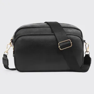 Detail of black faux leather crossbody bag with dual zippers and gold-tone hardware