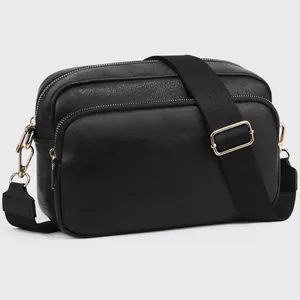 Detail of black leather crossbody bag with dual gold zippers and wide shoulder strap