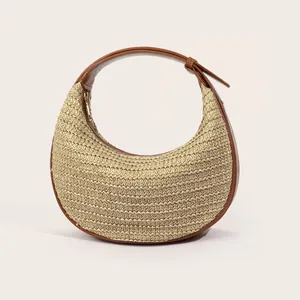 Detail of hand-woven crescent bag featuring brown leather trim and metal zipper closure