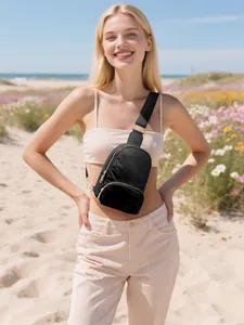 Modella all'aperto con borsa a tracolla in nylon nero e cerniere dorate sulla spiaggia