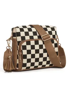 Detail view of jacquard crossbody bag with checkerboard pattern and brown tassel accent