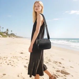 Detail of black pebbled PU leather crossbody bag with dual zippers and adjustable wide strap