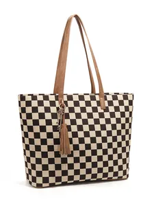 Détail du sac cabas à damier avec anses en cuir marron et pendentif à pampilles