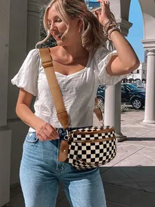 Close-up of checkerboard crossbody bag with brown wide strap and small coin purse