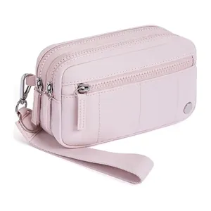 Détail du sac de poignet en nylon rose imperméable avec trois compartiments zippés