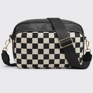 Close-up of checkerboard crossbody bag featuring gold hardware and black leather texture