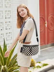 Detail of checkered crossbody bag with detachable earphone pouch and wide black shoulder strap