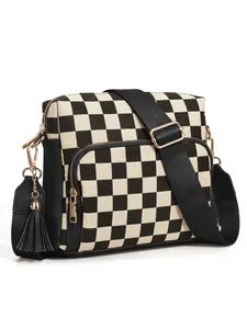 Detail of checkered canvas crossbody bag featuring black leather trim and decorative tassel