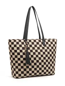 Détail du sac cabas à damier avec des anses en cuir et un pendentif à pampille noir