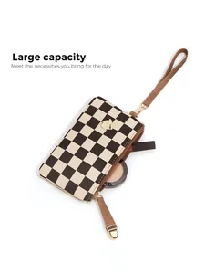Detail view of large capacity checkerboard wristlet pouch holding lipstick and compact