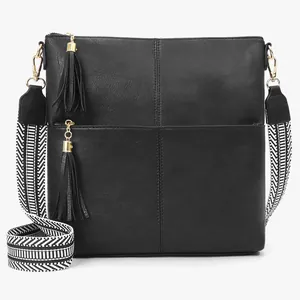 Close-up of black PU messenger bag featuring fringe tassels and a woven geometric strap
