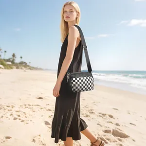 Fashionable black and white checkerboard crossbody bag with adjustable wide strap on beach