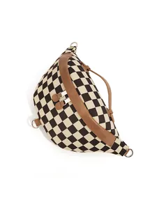 Close-up of checkerboard canvas chest bag featuring brown leather trim and silver zippers