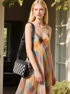 Détail du sac bandoulière à damier avec sangle en toile noire et fermetures éclair dorées