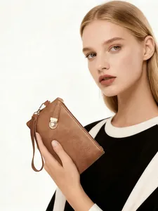 Detailed view of a brown pebbled leather wristlet clutch with a gold circular metal clasp