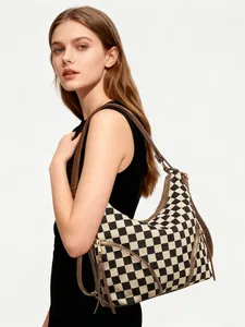 Checkerboard canvas shoulder bag featuring brown straps and metallic zipper details on model