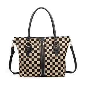 Detailed close-up of large checkerboard tote bag with dual zippers and golden hardware