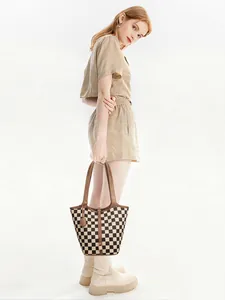 Dettaglio di un’elegante borsa shopper a scacchi con manici in pelle marrone