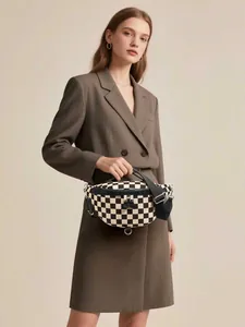 Close-up of checkered canvas chest bag with black leather trim and silver metal D-ring detail