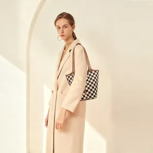 Borsa tote a scacchi bianchi e neri con manici in pelle marrone indossata da una modella