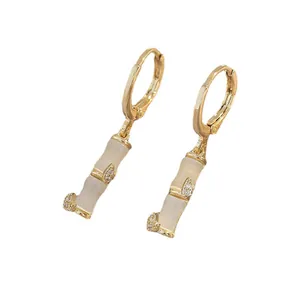 Bamboo style earrings with gold finish and white cat eye stone on a clean white backdrop