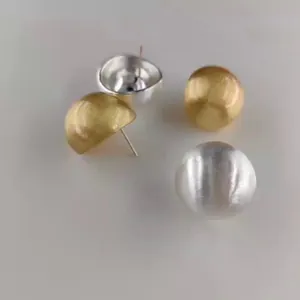 Vista dettagliata degli orecchini a sfera in metallo spazzolato oro e argento