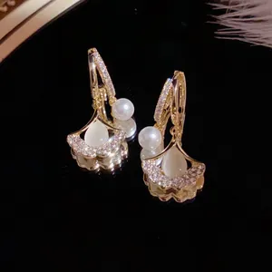 Elegant gold ginkgo leaf earrings with cat eye stone and hanging pearl detail