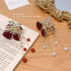 Macro view of velvet red roses and golden fringe tassels on a luxury hair claw clip