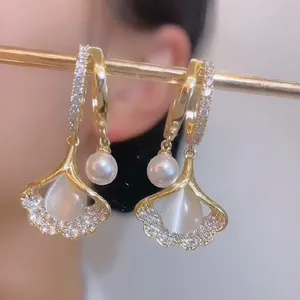 Elegant gold ginkgo leaf earrings with cat eye stones and dangling white pearls