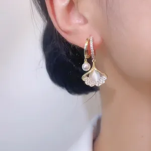 Detailed view of asymmetric ginkgo leaf earrings with pearls and pavé diamonds