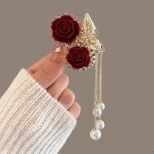 Macro detail of red velvet rose hair claw clip with crystal edges and pearl tassels