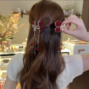 Detail showing red velvet rose hair claw with gold tassels and pearls on brown hair