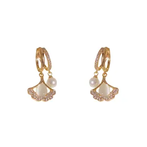 Macro detail of gold ginkgo leaf earrings with cat-eye stone, pearls and pavé zircons
