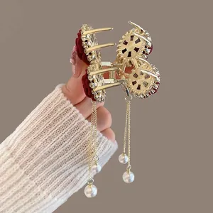 Detail of red velvet rose hair claw clip with golden chains and hanging white pearls