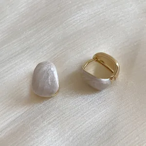 Detailed macro view of retro gold-plated earrings with white marble texture inlays