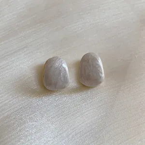 Detailed view of oval cream marble earrings with gold plated copper base and minimalist style
