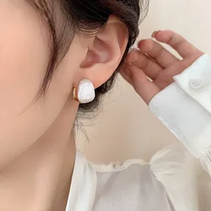 Irregular white resin earrings with gold trim on model for a minimalist vintage look